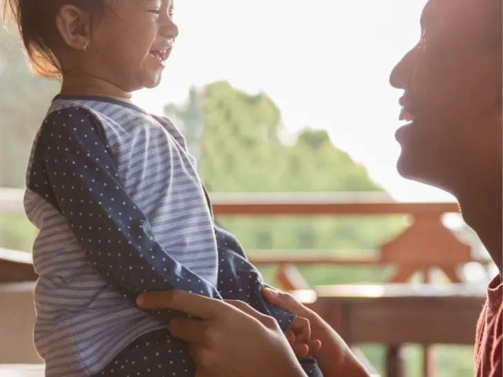 A father and his toddler son connecting and laughing holding hands