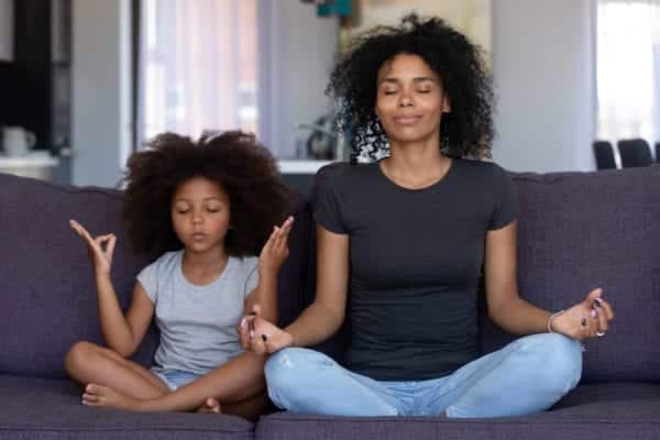 A mom and daughter meditating together.