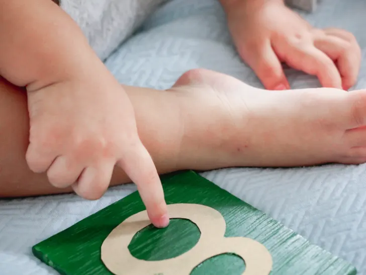 A young boy tracing a sandpaper numeral