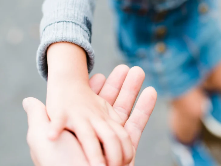 A young son reaching for his father's hand