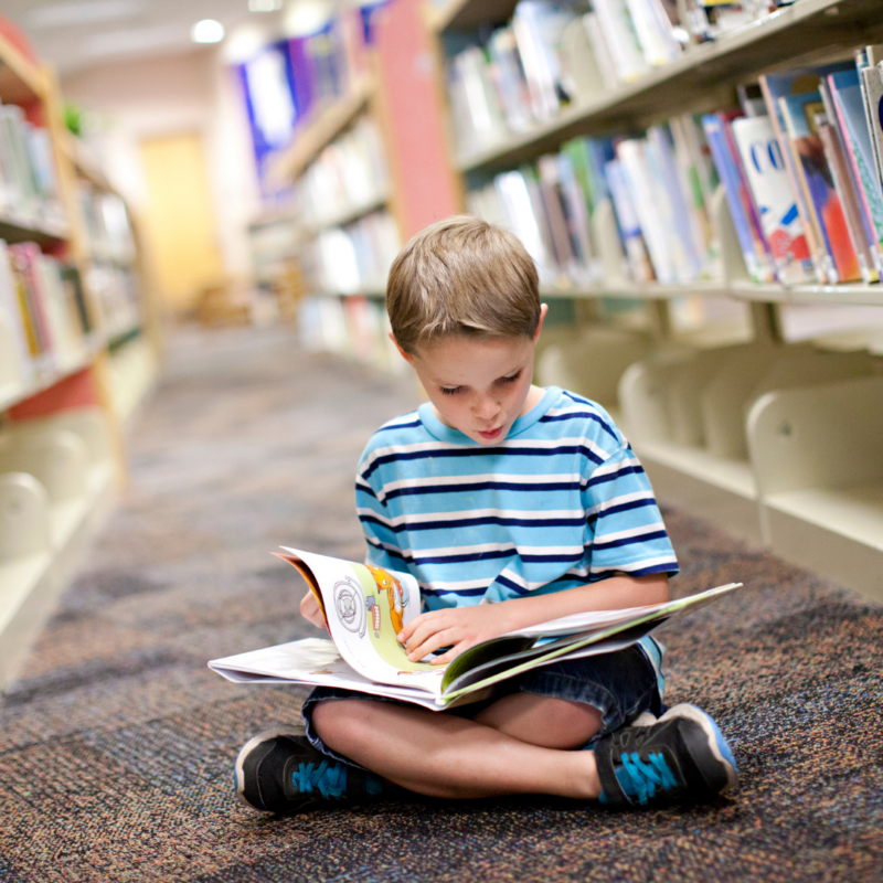 A young boy reading in a library aisle